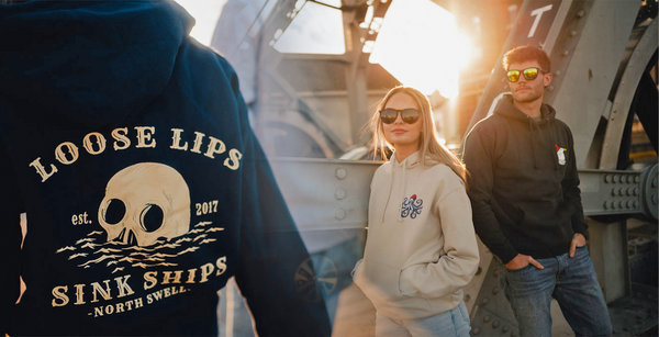 Two people wearing hoodies with visible branding in an outdoor setting.